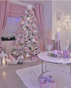 a living room decorated for christmas with pink and white decorations on the tree, candles, and presents