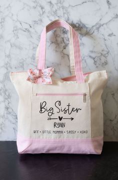 a pink and white tote bag sitting on top of a marble counter next to a wall