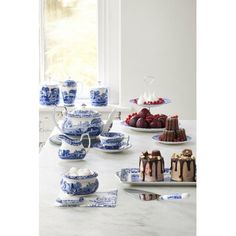 blue and white dishes with desserts on them sitting on a marble countertop in front of a window