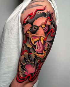 a man with a tattoo on his arm has a bear head and flames in the background