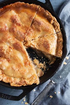 an apple pie in a cast iron skillet with one slice cut out and ready to be eaten