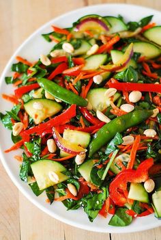 a white plate topped with veggies and nuts on top of a wooden table