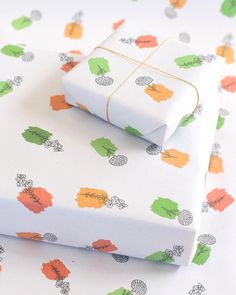 two wrapped presents sitting on top of each other next to an autumn themed wrapping paper