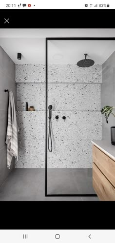 a bathroom with a walk in shower next to a sink and wooden drawers on the wall