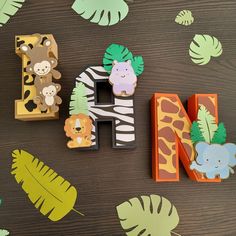 the letter n is made up of wooden letters with animals and leaves around it on a table