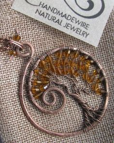 a wire wrapped brooch with a tree on it's side and a label for handmadewire natural jewelry