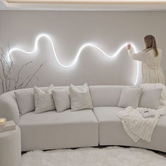 a woman standing on top of a white couch in front of a wall with lights