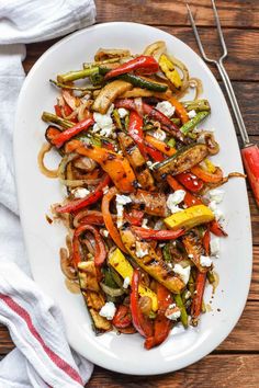 a white plate topped with assorted vegetables and feta cheese on top of it