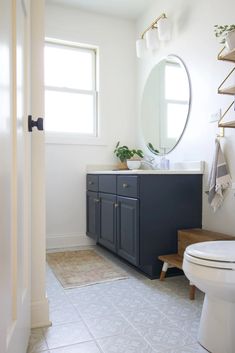 a white toilet sitting next to a bathroom sink under a large mirror on top of a wooden shelf