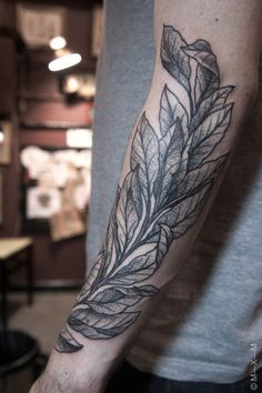 a man's arm with a leaf tattoo on it