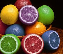 a bowl filled with different colored fruit sitting on top of a wooden table next to each other