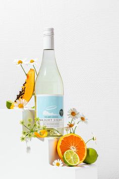 there is a bottle of wine with oranges and daisies