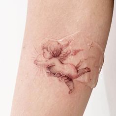 a tattoo on the leg of a woman with an angel in her arms and wings