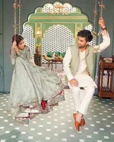 a man and woman sitting on swings in a room