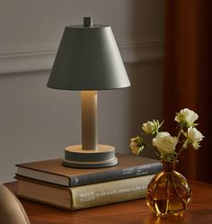 a table lamp sitting on top of a book next to a vase with flowers