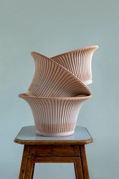 a white vase sitting on top of a wooden stool