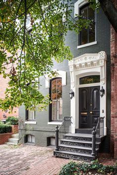 a black door and some steps in front of a gray house with white trim on the windows