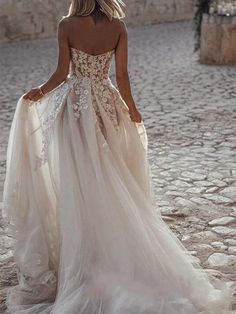 a woman in a wedding dress is walking down the street with her back to the camera