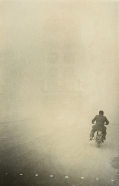 a man riding a motorcycle down a foggy street