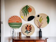 three woven plates on top of a wooden table next to a vase with flowers in it