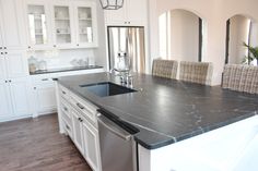 a kitchen with white cabinets and black counter tops, along with a stainless steel dishwasher