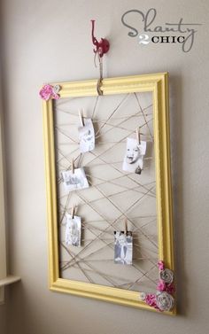 a yellow frame hanging on the wall with clothes pins and pictures pinned to it's sides