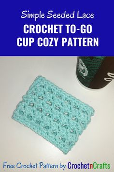 a crochet square sitting on top of a table next to a cup