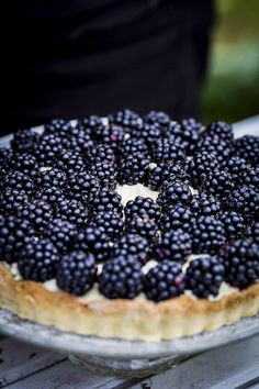 a pie topped with blackberries on top of a wooden table