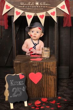 a baby is sitting on top of a wooden crate with hearts and a sign that says kisses 25