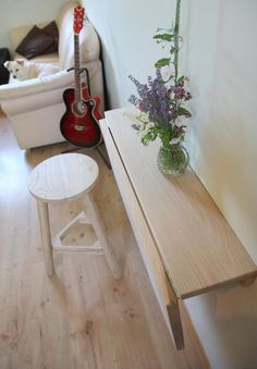 a vase with flowers sitting on top of a wooden table next to a white chair