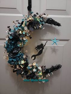 a wreath is hanging on the front door with an image of a mermaid and starfish