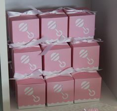 several pink boxes with white ribbons are stacked on top of each other in a shelf