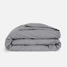 the grey and white striped comforter is folded on top of each other, with two pillows