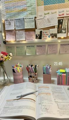 an open book sitting on top of a desk next to some pens and pencils