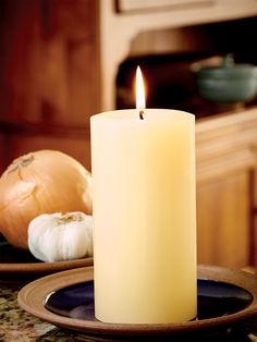 a lit candle sitting on top of a plate next to an onion and clove