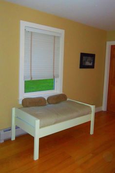 a bed with two pillows on top of it in a bedroom next to a window