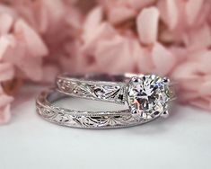 two wedding rings sitting next to pink flowers