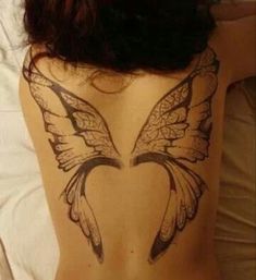 the back of a woman's body with a butterfly tattoo on her lower back