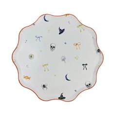 a white plate with orange trim and halloween decorations on it, sitting on a white surface