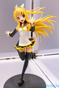 a figurine is posed on top of a black and white base with yellow hair