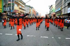 a group of people in orange outfits are marching down the street with their arms up