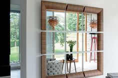 a mirror reflecting the inside of a room with furniture in front of it and trees outside