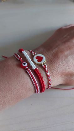 a woman's arm wearing two bracelets with red and white beads on it