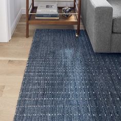 a living room with a gray couch and blue rug