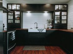 a kitchen with wooden floors and black cabinetry is pictured in this image from the front view