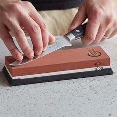 a person using a large knife to cut up something on a counter top with a sharpener