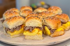 mini burgers are arranged on a plate with cheese and black sesame seed sprinkles