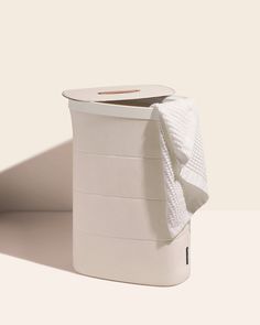 a roll of toilet paper sitting on top of a white container with a towel wrapped around it