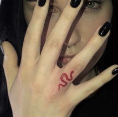 a woman with black nails holding her hand up to her face and the letter s painted on her fingers