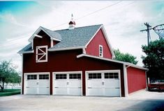 a large red barn with two garages on each side